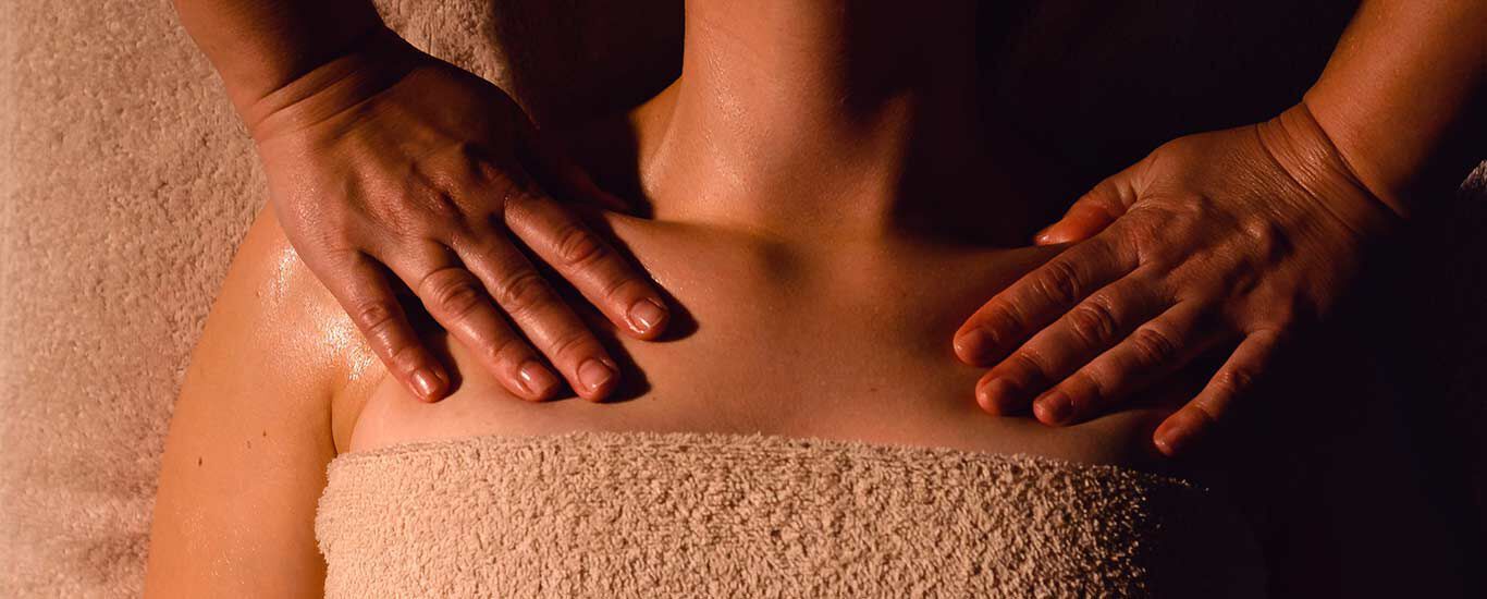 Vrouw ligt op een bank en krijgt lymfedrainage op haar schouderbeenderen. 